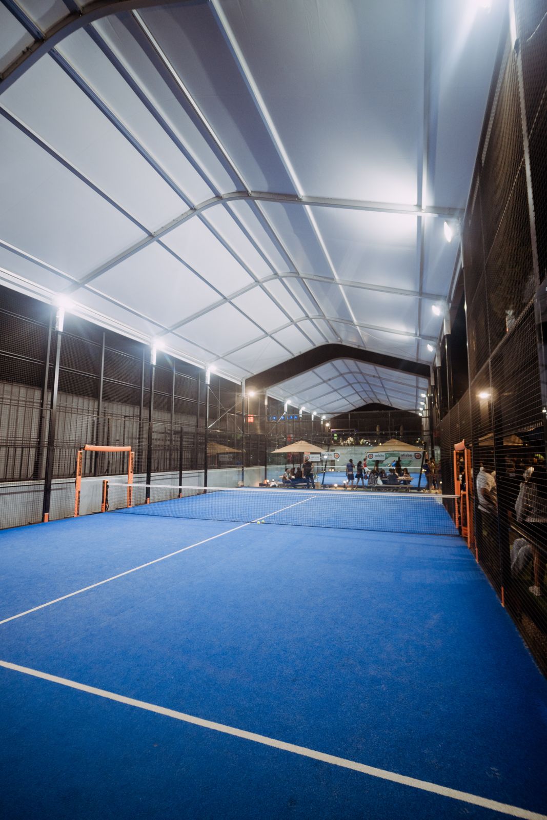 Indoor padel court with blue surface and covered canopy